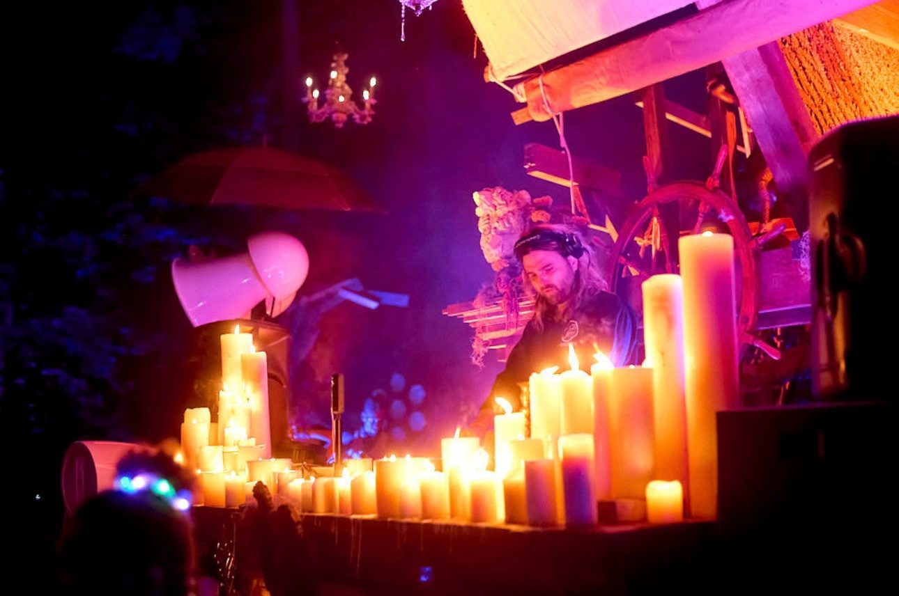 A DJ at a candlelit booth washed in purple light, a Void horn beside him